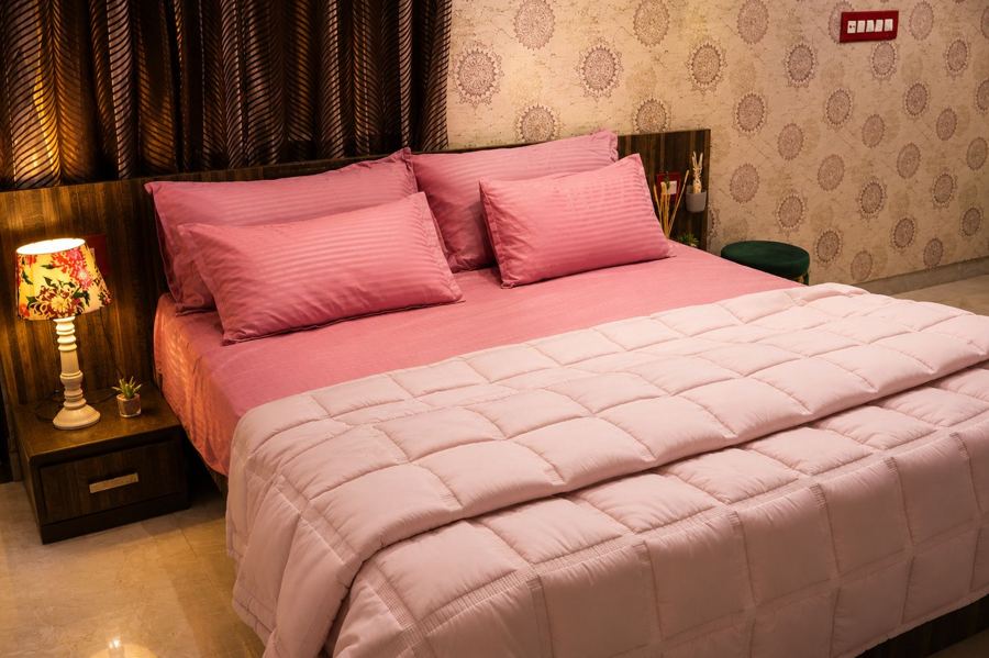 Bedroom with rose-pink linen and a table lamp